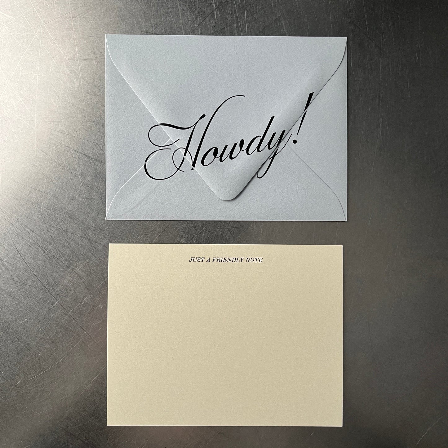 Card & envelopes on a reflective surface, one with calligraphy and the other plain.