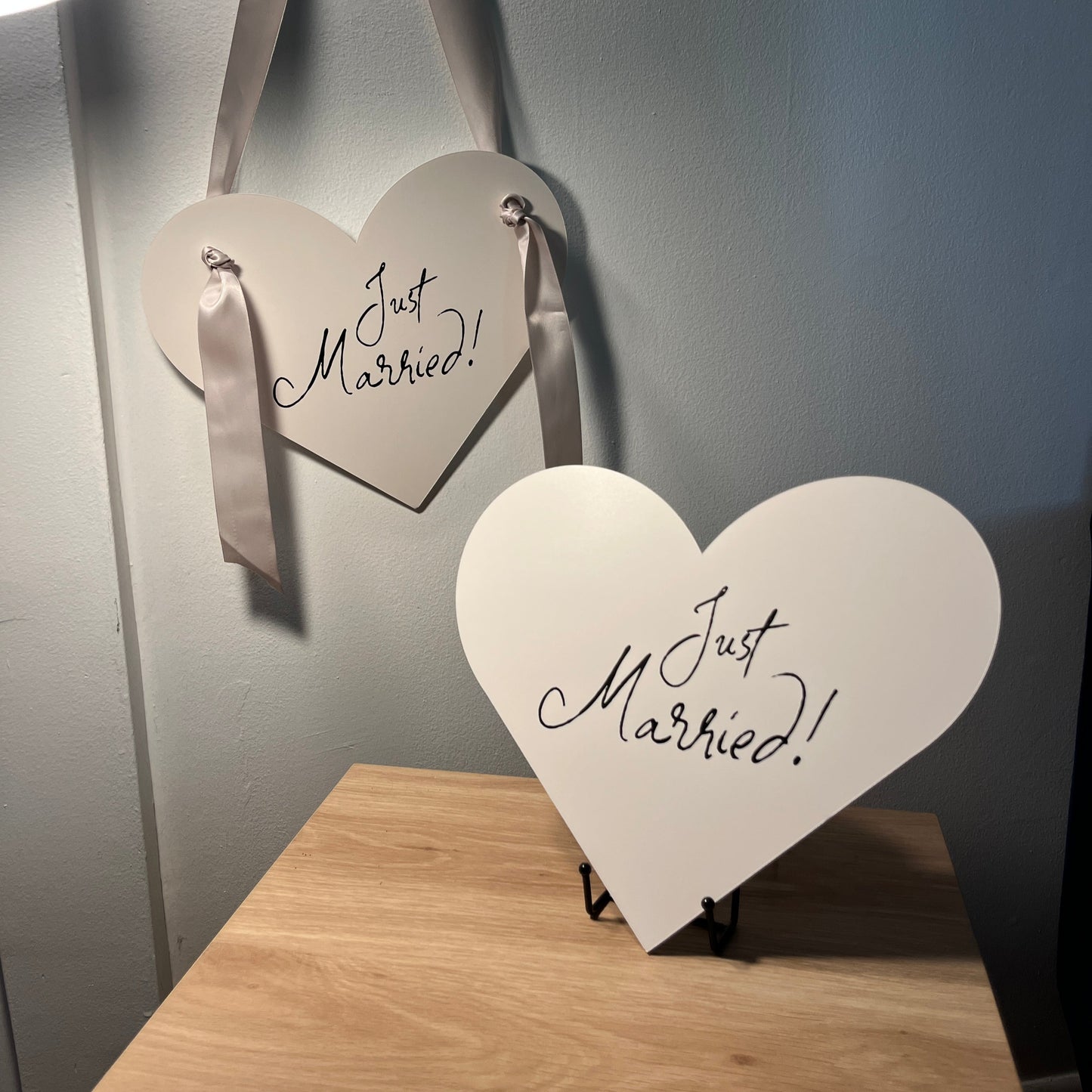 Heart-shaped 'Just Married' signs on a wooden stand with a neutral background